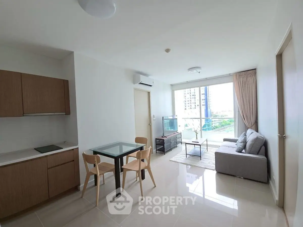 Modern open-plan living room with kitchen and balcony view in high-rise apartment