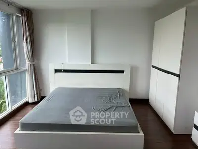 Spacious bedroom with large windows and modern furniture in a bright apartment.