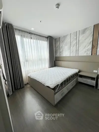 Modern bedroom with large window and stylish decor in a contemporary apartment.