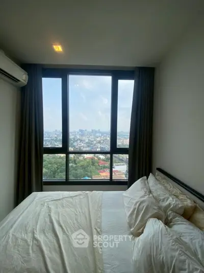 Cozy bedroom with stunning city view through large windows, perfect for urban living.