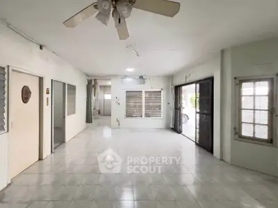 Spacious open-plan living area with tiled flooring and ceiling fan, ideal for customization.