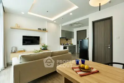 Modern living room with open kitchen, sleek furniture, and stylish decor in a contemporary apartment.