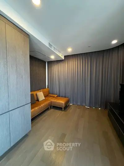 Modern living room with sleek wooden flooring and stylish leather sofa, perfect for contemporary living.
