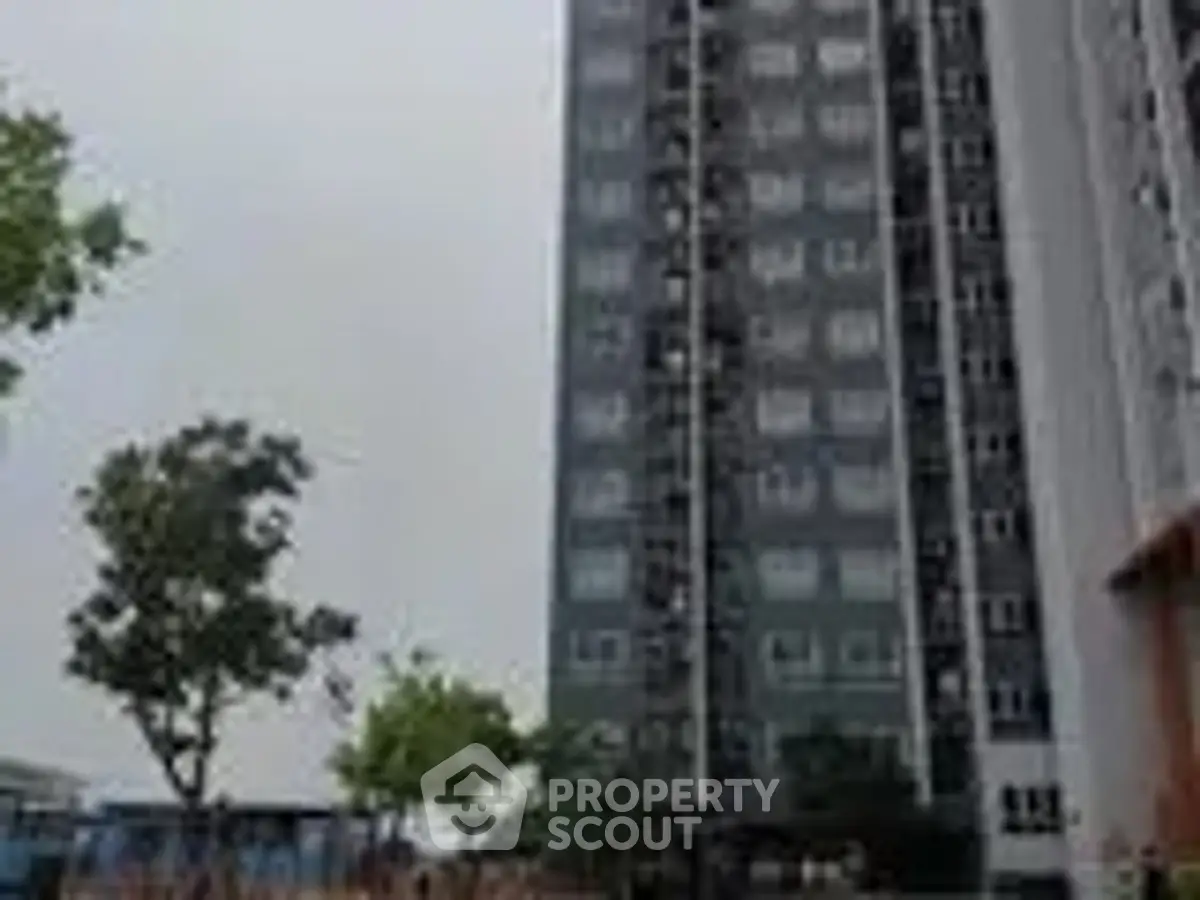 Modern high-rise apartment building with lush greenery and urban setting.