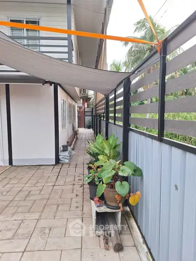 Charming outdoor patio with potted plants and modern fencing, perfect for relaxation.