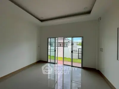 Spacious empty room with large windows and garden view, perfect for customization.