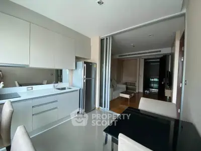 Modern open-layout kitchen with sleek cabinetry and dining area in stylish apartment.
