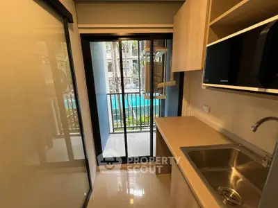 Modern kitchen with pool view, sleek cabinetry, and stainless steel sink in a compact layout.