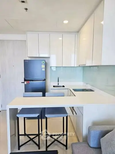 Modern kitchen with sleek white cabinets and breakfast bar in a stylish apartment.