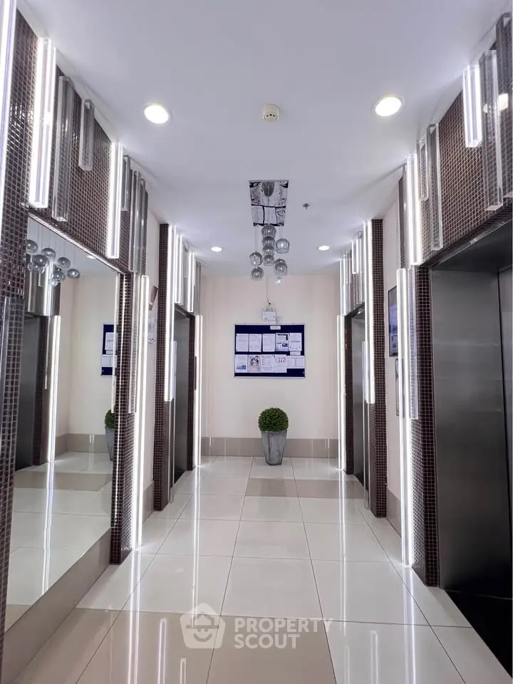 Modern elevator lobby with sleek lighting and polished tile flooring in a contemporary building.