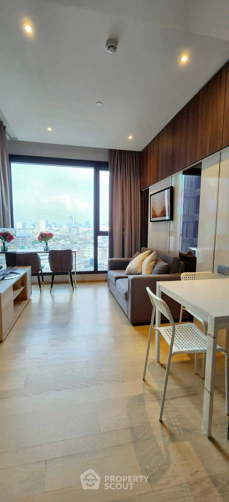 Modern living room with city view, stylish furniture, and natural light.