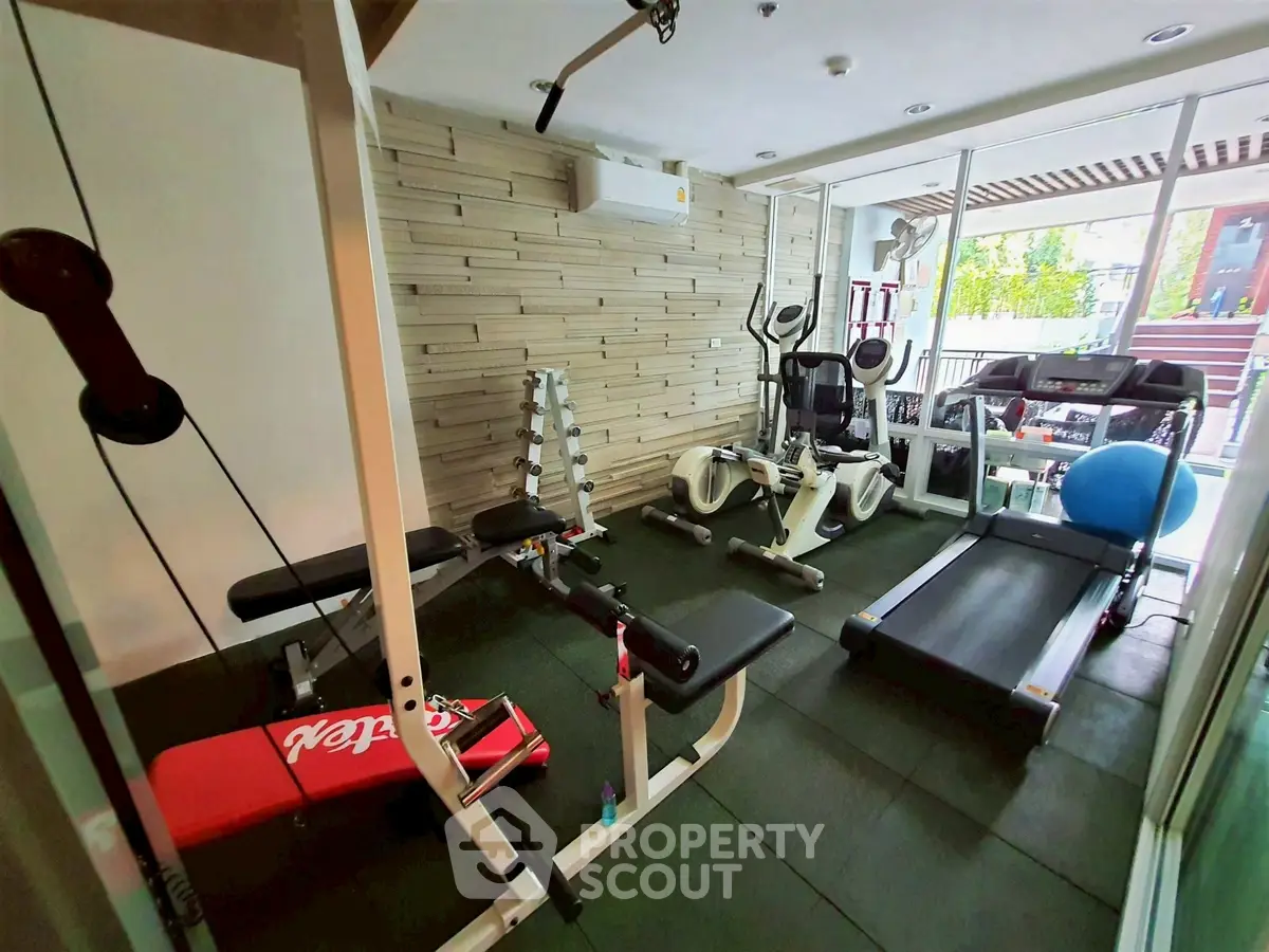 Modern home gym with treadmill, weights, and exercise equipment in a bright room.