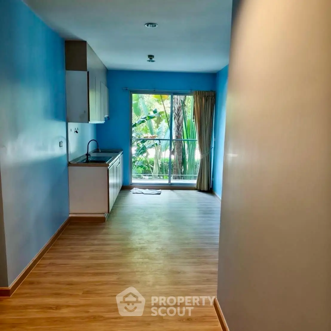 Bright kitchen with open layout and large window overlooking lush greenery.