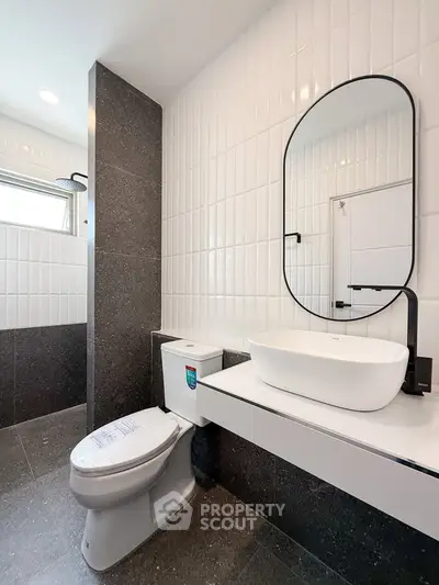 Modern bathroom with sleek design, featuring a stylish oval mirror and contemporary fixtures.