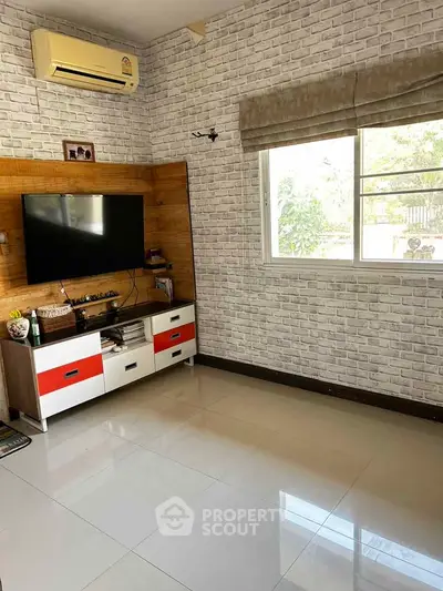 Modern living room with TV, air conditioning, and stylish brick wall decor.
