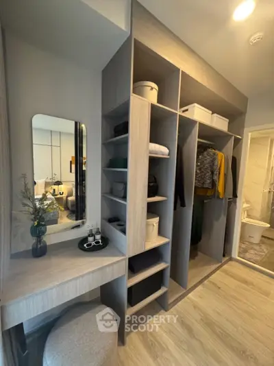 Modern walk-in closet with stylish shelving and vanity area in a contemporary apartment.