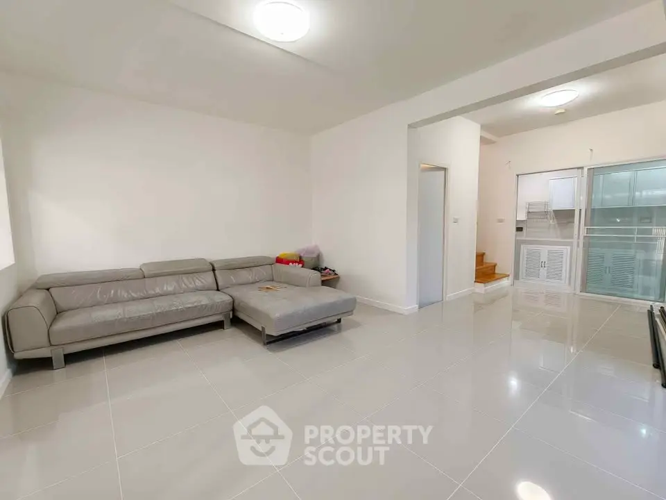 Spacious modern living room with sleek gray sectional sofa and glossy tiled flooring.