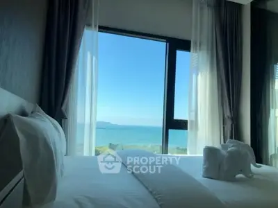 Luxurious bedroom with stunning ocean view through large windows.