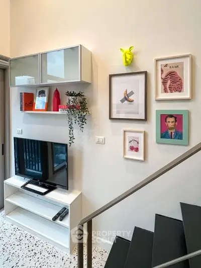 Stylish modern living room with TV, wall art, and staircase