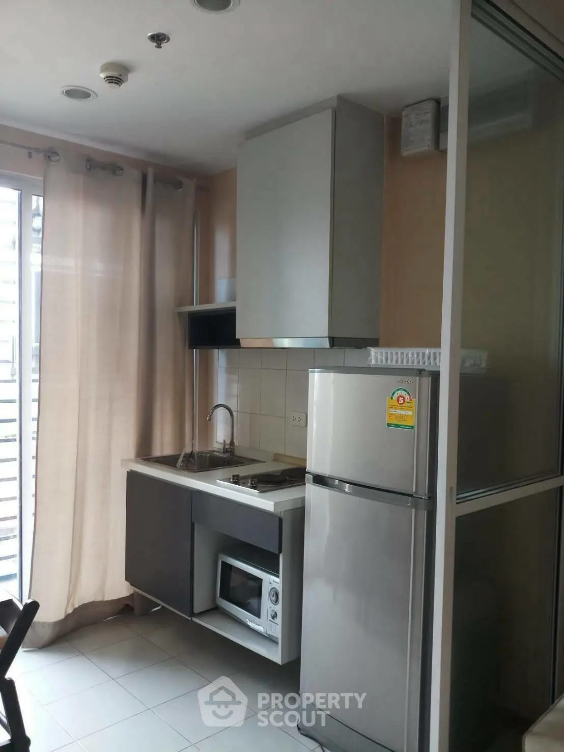 Modern compact kitchen with stainless steel appliances and natural light