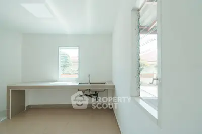Minimalist kitchen with sleek countertops and large windows for natural light.