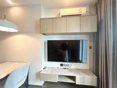 Modern living room with wall-mounted TV and air conditioning unit, featuring sleek furniture and elegant lighting.