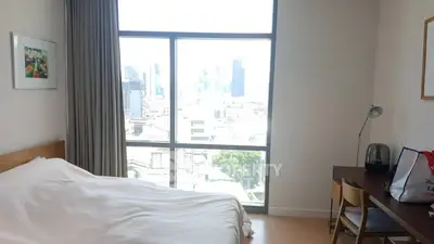 Bright bedroom with city view, modern furniture, and large window.