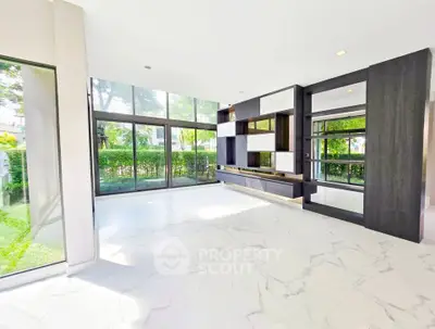 Spacious modern living room with large windows and marble flooring, offering a bright and airy atmosphere.