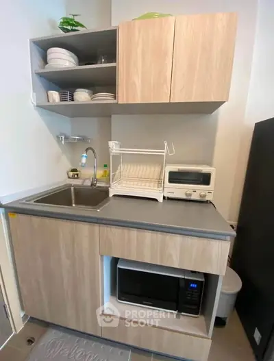 Compact modern kitchen with wooden cabinets and appliances, ideal for small spaces.