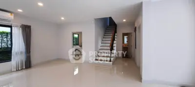 Spacious modern living room with staircase and large windows, perfect for family gatherings.