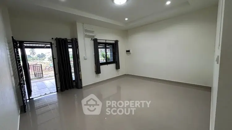 Spacious empty living room with large windows and open entrance to garden.