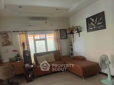 Cozy living room with brown leather sofa and wall art, featuring a window and air conditioning.