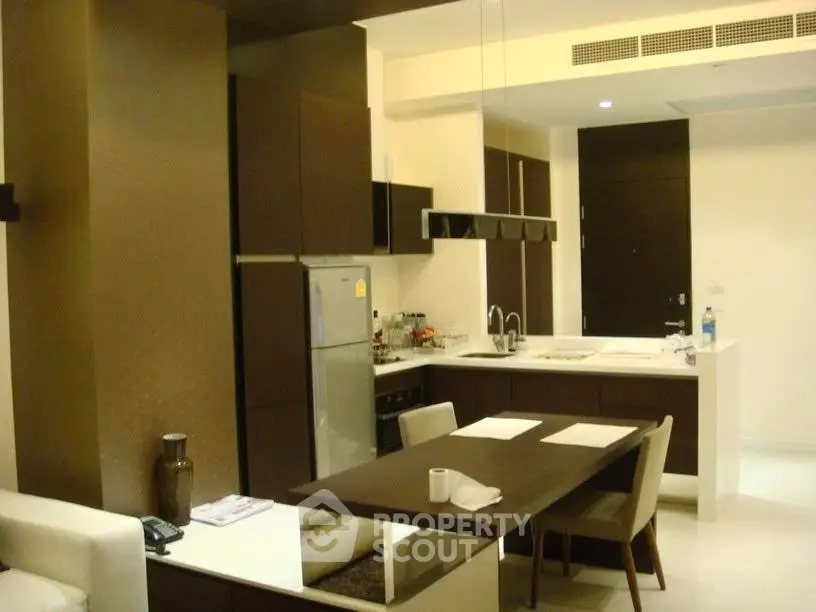 Modern kitchen with sleek design, featuring dark wood cabinets, built-in oven, and stylish dining area.