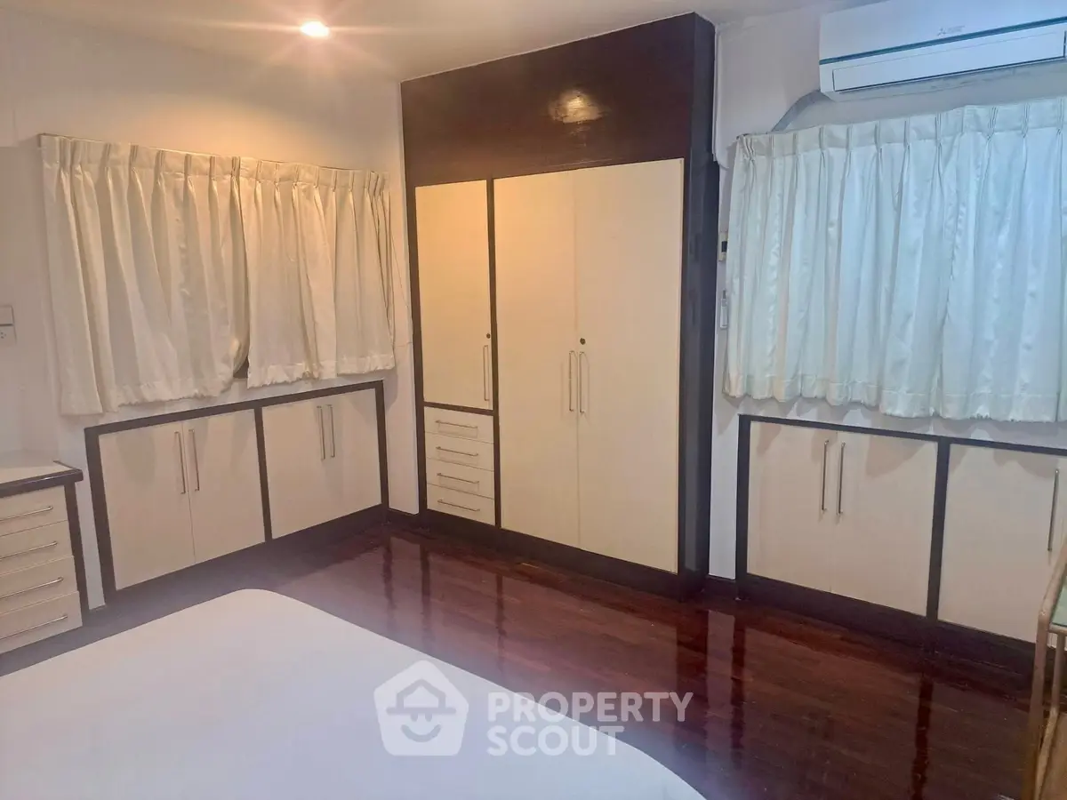 Spacious bedroom with elegant wooden flooring and ample storage space.