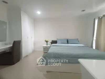 Spacious bedroom with modern decor and ample natural light, featuring a comfortable bed and stylish furnishings.