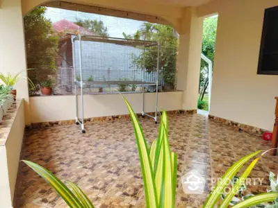 Spacious tiled patio with greenery, perfect for outdoor relaxation.