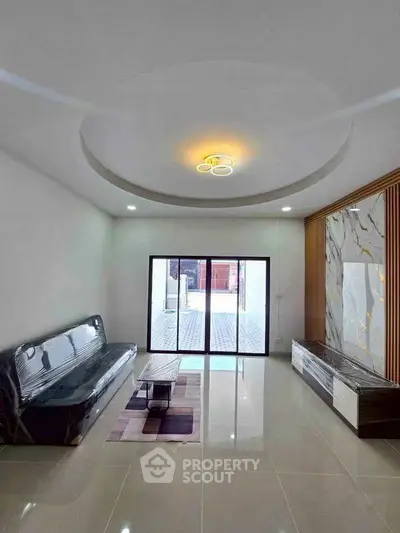 Spacious modern living room with elegant ceiling design and large glass doors.