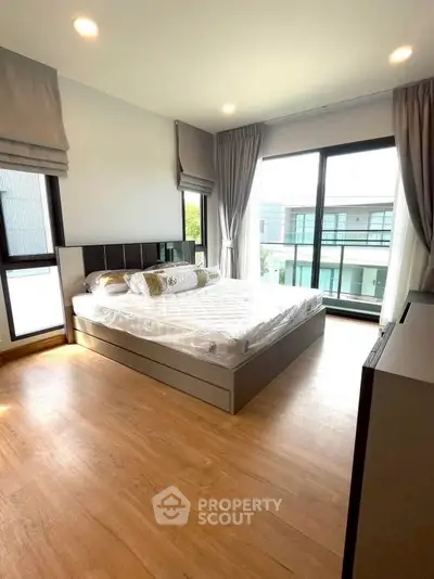 Spacious modern bedroom with large windows and wooden flooring in a contemporary home.