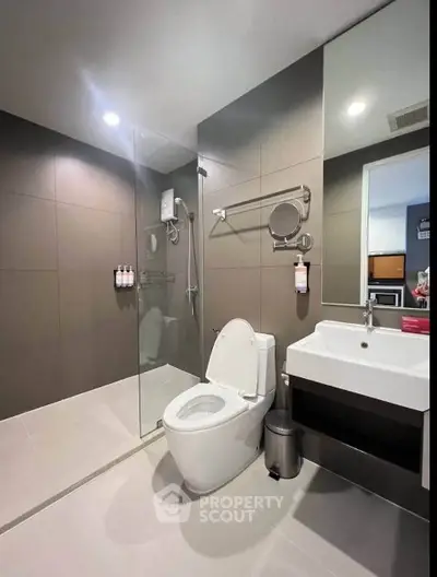 Modern bathroom with glass shower and sleek fixtures in contemporary apartment.