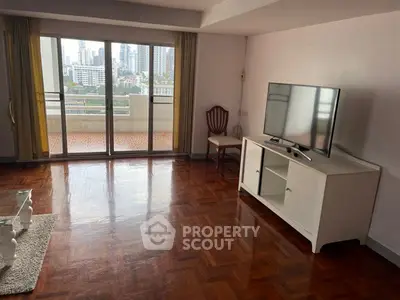 Spacious living room with parquet flooring and city view balcony in modern apartment.