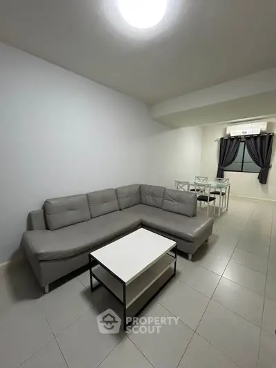 Spacious modern living room with sleek gray sectional sofa and dining area, perfect for entertaining.