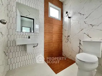 Modern bathroom with stylish tiles and sleek fixtures, featuring a shower and toilet.