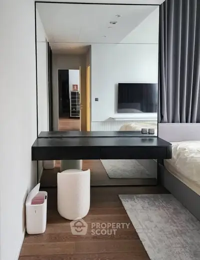 Modern bedroom with sleek vanity, large mirror, and stylish decor