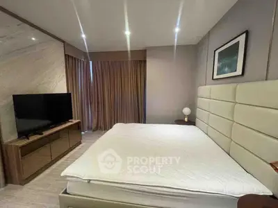 Modern bedroom with stylish decor and large TV, perfect for relaxation.