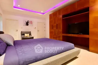 Luxurious bedroom with modern lighting and built-in wooden entertainment unit.