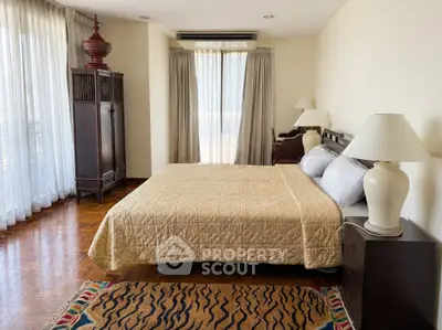Spacious bedroom with elegant decor and large windows offering natural light.