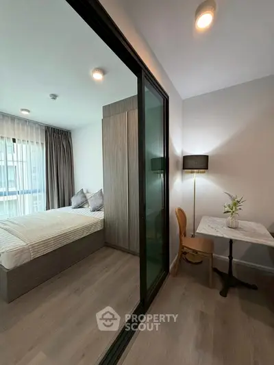 Modern bedroom with glass partition and cozy study area in a stylish apartment.