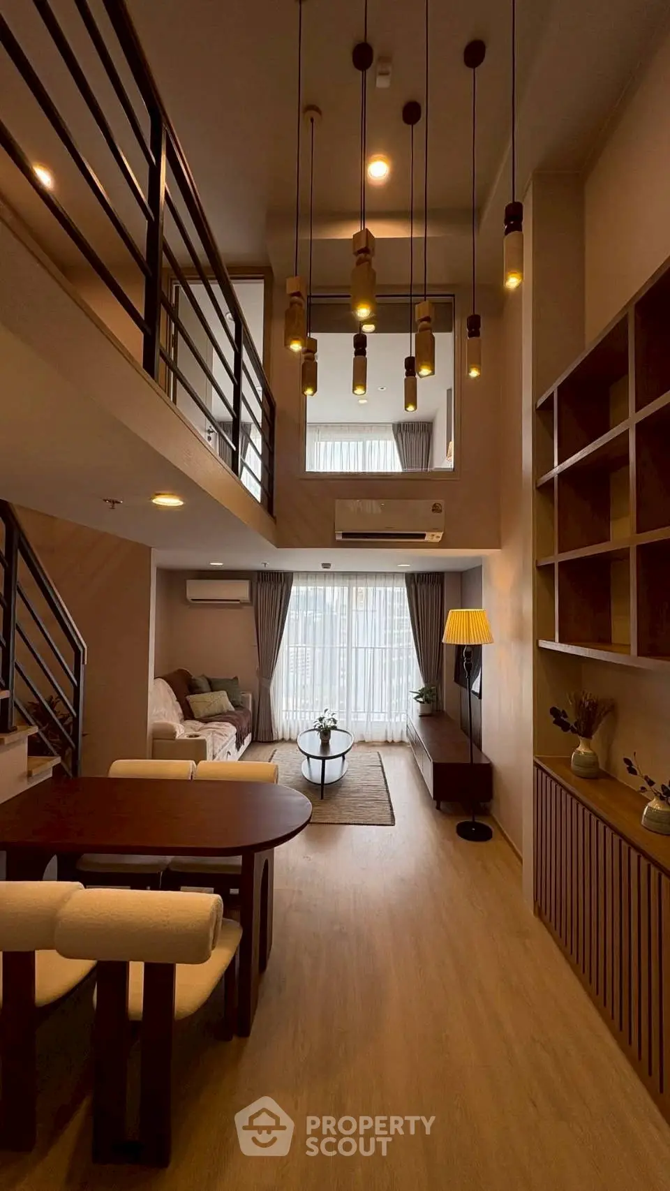 Modern duplex living room with high ceiling and stylish lighting, featuring cozy seating and elegant decor.