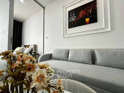 Modern living room with stylish decor and cozy gray sofa, featuring elegant wall art and fresh floral arrangement.