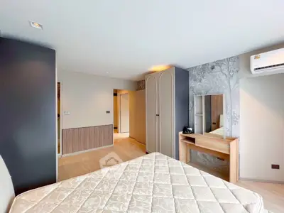 Spacious bedroom with modern decor and natural light, featuring a stylish wardrobe and vanity area.